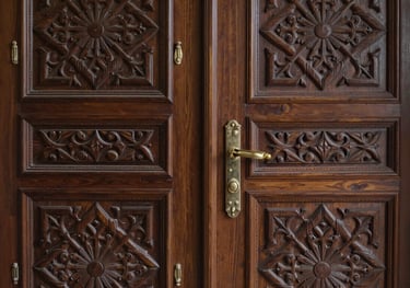 A detailed shot of hand-carved dark brown wooden doors in a Middle Eastern / Saudi Arabian style, symbolizing the high quality and craftsmanship of the hotel.