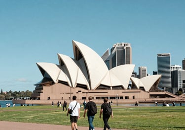 Clean, bright photography of the Sydney Opera House and modern city skyline. International Student / Global Audience walking in a clean urban park under a bright blue sky.