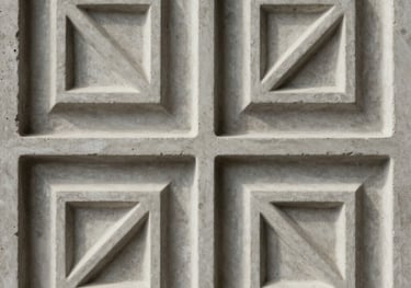 Detail of a decorative wall ornament with a modern geometric relief pattern, made from refined concrete, soft shadows highlighting the 3D texture.
