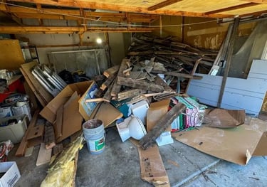garage full of construction debris like wood, drywall and trash