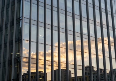 High-end corporate building facade with sleek glass panels reflecting a golden sunset, symbolizing growth and authority. Global / High-end corporate.