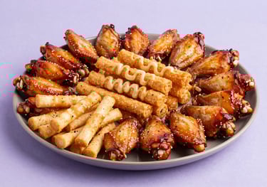 A large sharing platter of party snacks like chicken wings and cheese sticks. The lighting is vibrant with pale cloud lavender highlights.