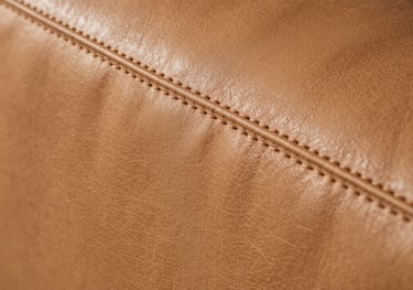 Close-up of a high-end tan leather surface with perfect stitching, shot in warm natural light. The texture is soft and inviting, North American boutique feel.