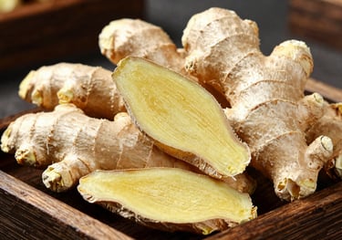 Clean, peeled dry ginger pieces arranged on a rustic tray. The image captures the pale, sandy color and fibrous texture of the ginger against a dark background.
