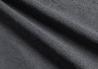Clean, studio photography showing the texture of a charcoal grey linen fabric. The lighting is soft, emphasizing the natural weave of the textile.