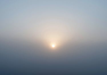 A minimalist scene of a sun rising through morning mist, symbolizing the start of a circadian-aligned day. Colors #F0F5F7 and #AABEC6 dominant.