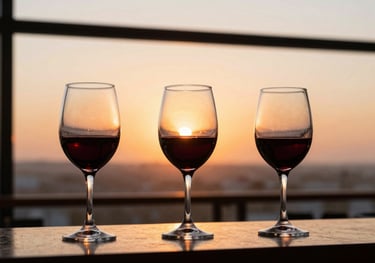 Three glasses of red wine lined up on a bar counter during a professional event, orange sunset light coming through the window of a Latin American skybar.