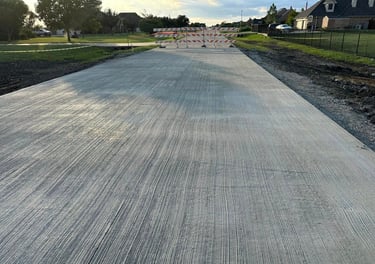 Freshly poured concrete road with barricades ahead.