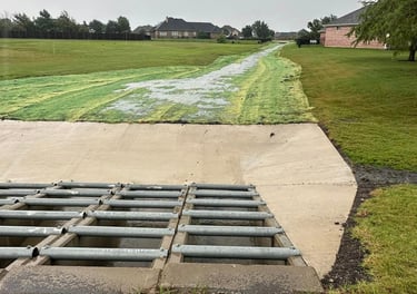 Concrete drainage channel with metal grate.