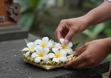 Intimate close-up of a Balinese offering being placed on a temple step, hands arranging frangipani flowers in a woven palm leaf tray, morning light, soft green background, no tourists, natural gesture