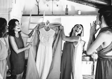 La sposa e la damigella d'onore preparano divertite l'abito da sposa