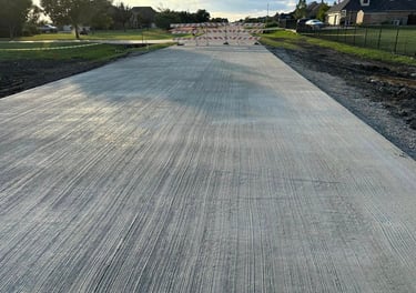 Freshly poured concrete road with barricades ahead.