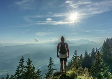una mujer mirando al horizonte desde lo alto de una montaña