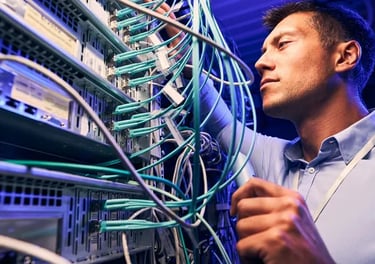 IT technician managing ethernet cables and network servers in a modern data center.