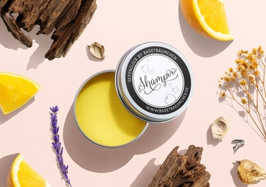 Natural solid shampoo bar in a tin surrounded by fresh orange slices, lavender, and wood.