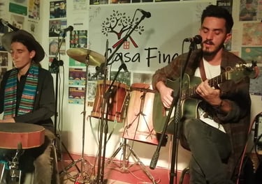 Dos músicos interpretan una sesión acústica en vivo con una guitarra y un tambor de mano en Casa Fin