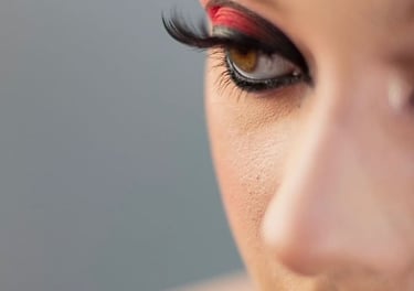 Primer plano del dramático maquillaje de ojos de una mujer con sombras rojas y negras y pestañas pos