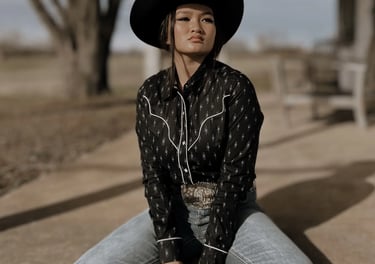 Woman sitting on a porch in a western shirt and jeans