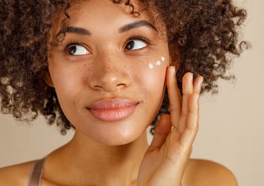 young woman applying moisturizer to face