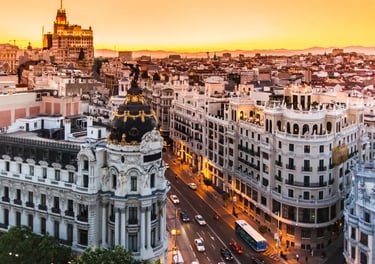 Aerial view of Madrid city skyline at sunset featuring the iconic Metropolis Building on Gran Via.