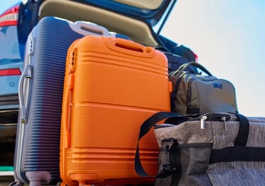 Suitcases and travel bags packed behind a car trunk for a family road trip.