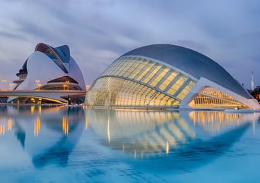 Modern architecture of the City of Arts and Sciences in Valencia reflecting in water at twilight.