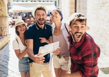 Cheerful group of young tourists laughing while exploring a sunlit European city street with a paper map.