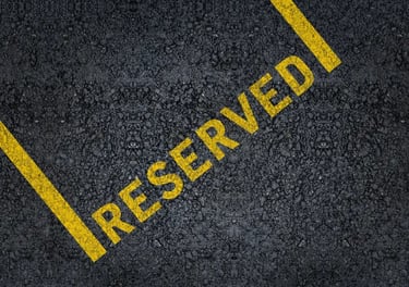 Yellow painted reserved sign on black asphalt surface of a parking lot space.