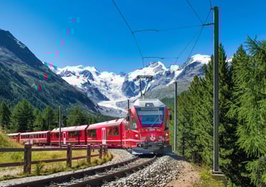 Red Bernina Express train traveling through the Swiss Alps with snowy mountain peaks and a glacier.