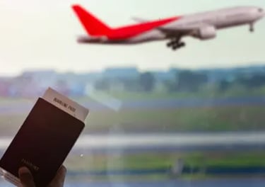 A traveler holding a passport and boarding pass at the airport as a plane takes off.