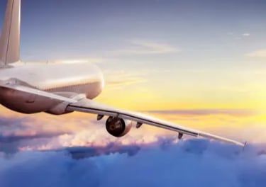 A commercial airplane flying high above white clouds during a vibrant golden sunset.