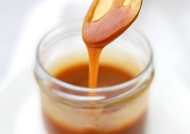 cuchara con dulce de leche en vaso de vidrio
