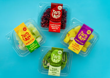 mėlyname fone padėti pjaustytų ananasų, melionų, kivių bei lukštentų granatų indeliai