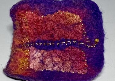 a small square shaped object with a purple and gold colored design