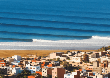 a view of a beach with a surfboarder in the foreground