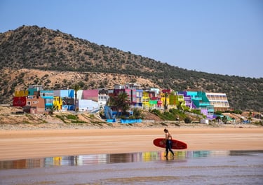 a person holding a surfboard while walking on the beach