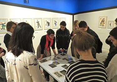 a group of people standing around a table with pictures on it