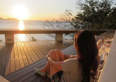 a woman sitting on a couch with a view of the ocean