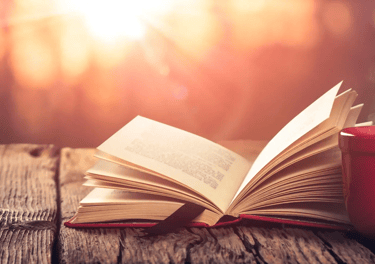 a book on a table outside with a cup of coffee
