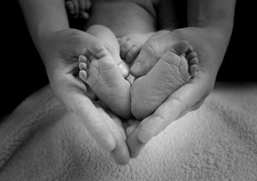 Manos de una madre y pies de un bebé con forma de corazón