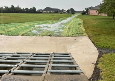 Concrete drainage channel with metal grate.