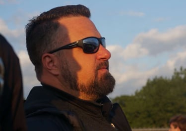 a man with a beard and sunglasses on a sunny day