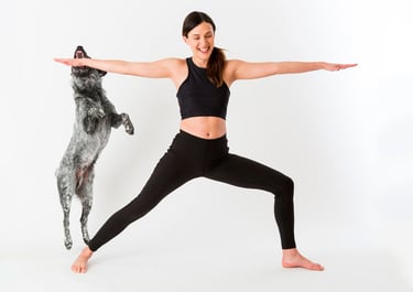a woman in a black top and leggings and a dog standing in front