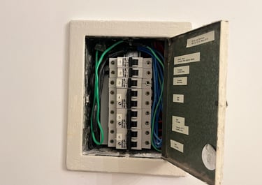 Open residential electrical panel with labeled circuit breakers and colorful wiring for home power distribution.