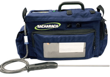 Bacharach gas analyser in a blue soft carrying case with a metal probe and hose attachment.
