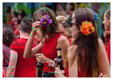 Frauen mit Blumen im Haar in roten Kleidern trinken Bier.