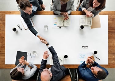 a group of business people shaking hands over a table