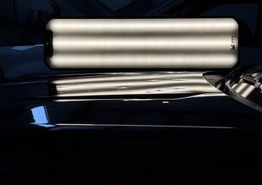 Professional LED light panel used for paintless dent repair on a car hood in a dark shop.