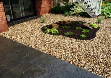 Platebande en gravier avec roches, paillis et plantes décoratives par M2 Paysage
