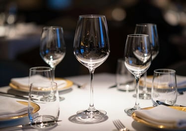 Elegant table setting in a high-end restaurant featuring premium glassware and minimal golden accents, dramatic side-lighting, 35mm